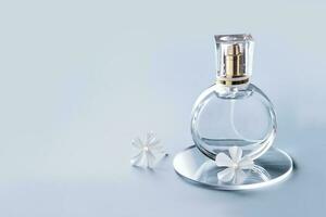 Glass perfume bottle, white flowers and round slides on blue background. Winter or spring floral fragrance photo