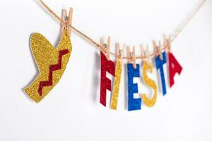 Fiesta word and sombrero made of shiny paper on pins. Fragment of festive DIY Garland of interior. Cinco de mayo celebration photo