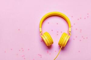 Yellow headphones and confetti on pink background. Minimal Music concept, flat lay, copy space photo