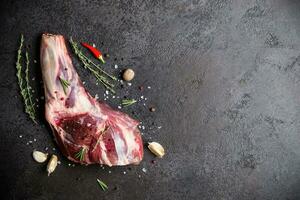 Raw fresh Lamb Meat shank and seasonings on black stone background photo