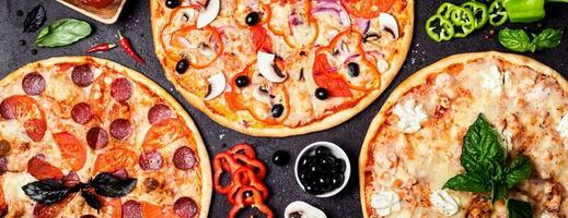 selección de diferente pizzas en un negro antecedentes y ingredientes. salchichón, vegetariano y Mariscos Pizza foto