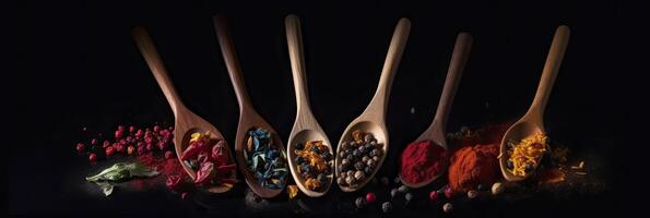 A row of wooden spoons filled with different types of spices on black background. photo