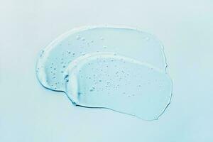 Liquid abstract cosmetic gel smears on blue background. Smear of transparent moisturizing product photo