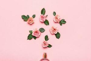 Bottle of perfume and roses flowers on pink background. Minimal beauty concept photo