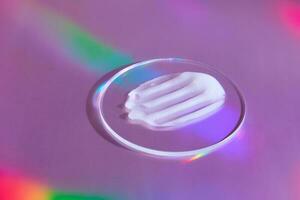 Smear of cream in petri dish on holographic background with iridescent highlights photo