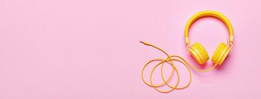 Yellow headphones on pink banner. Minimal Music concept, flat lay, copy space photo