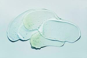 líquido resumen cosmético gel frotis en azul antecedentes. frotis de transparente hidratante producto foto