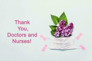 Thank You Doctor and Nurses concept with medical mask and lilac flowers photo