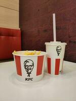 Stavropol, RUSSIA - April 2023 KFC fast food restaurant. A glass of milkshake and a box of french fries stand on a table inside a restaurant photo