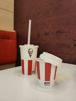 Stavropol, RUSSIA - April 2023 KFC fast food restaurant. A glass of milkshake with a straw and a glass of coffee stand on a table inside a restaurant photo