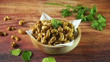 Cashew Nut, in Indonesia known as Kacang Mete or Mede, Served in a bowl on wood background, with hand video