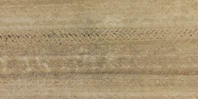 panorama of surface from above of gravel road with car tire tracks photo