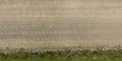 panorama of surface from above of gravel road with car tire tracks with roadside and grass photo