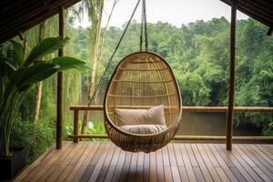 Wicker rattan hanging chair on wooden bamboo terrace in the jungle. photo