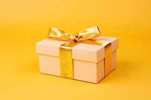 Gift box with golden satin ribbon and bow on yellow background. photo