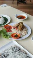 Rice with chicken and vegetables in a white plate on the table photo