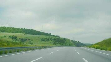 A spinning wind turbine next to the road on a summer and sunny day. video