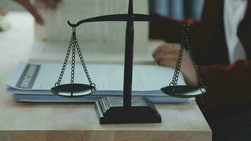 Business and lawyers discussing contract papers with brass scale on desk in office. Law, legal services, advice, justice and law concept picture with film grain effect video