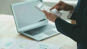 Asian Business woman using calculator and laptop for doing math finance on an office desk, tax, report, accounting, statistics, and analytical research concept video