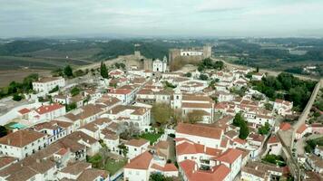 escénico ver de blanco casas, rojo embaldosado techos y castillo desde pared de fortaleza en obidos aldea, Portugal - aéreo zumbido Disparo video