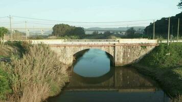 reflexões através calma rio com pedra arco ponte durante dia às alcobaça rio perto Nazare dentro Portugal. - aéreo puxar tiro video