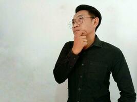Young man wearing casual clothes thinking concentrated about doubt with finger on chin and looking up wondering photo