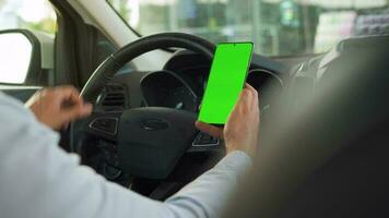 Driver using a smartphone inside the car. Chromakey smartphone with green screen. Auto navigation video