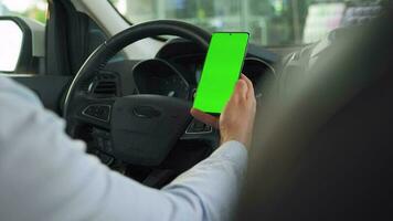 Driver using a smartphone inside the car. Chromakey smartphone with green screen. Auto navigation video