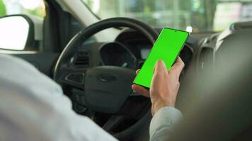 Driver using a smartphone inside the car. Chromakey smartphone with green screen. Auto navigation video