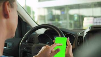 chauffeur en utilisant une téléphone intelligent à l'intérieur le auto. chromakey téléphone intelligent avec vert filtrer. auto la navigation video