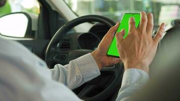 Driver using a smartphone inside the car. Chromakey smartphone with green screen. Auto navigation video