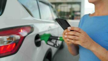 donna utilizzando smartphone mentre sua auto è rifornimento carburante video