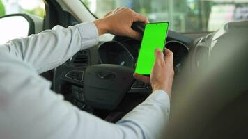 Driver using a smartphone inside the car. Chromakey smartphone with green screen. Auto navigation video