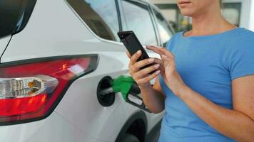 mulher usando Smartphone enquanto dela carro é reabastecimento video