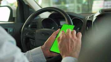 Driver using a smartphone inside the car. Chromakey smartphone with green screen. Auto navigation video