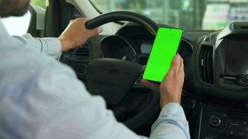 Driver using a smartphone inside the car. Chromakey smartphone with green screen. Auto navigation video