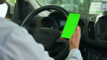 chauffeur en utilisant une téléphone intelligent à l'intérieur le auto. chromakey téléphone intelligent avec vert filtrer. auto la navigation video