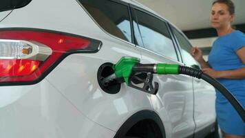 Woman pulls out a refueling gun from a car tank after finishing refueling video