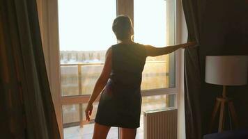 Frau steht in der Nähe von das Fenster und nimmt Bilder von das Rahmen Sonne auf ein Smartphone video