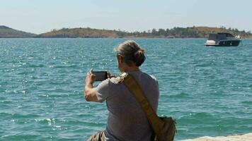 mayor viajero hombre capturar marina en playa con móvil teléfono video