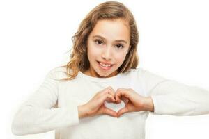 Young girl looking at camera showing heart gesture with two hands isolated on white background photo