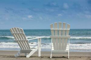 Empty white wooden chairs at a paradisiac beach on the tropics in a beautiful sunny day photo