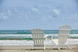 Empty white wooden chairs at a paradisiac beach on the tropics in a beautiful sunny day photo