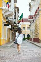 Beautiful woman on white dress walking alone at the streets of the colonial walled city of Cartagena de Indias photo