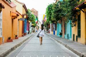 hermosa mujer en blanco vestir caminando solo a el vistoso calles de el colonial amurallado ciudad de cartagena Delaware indios foto