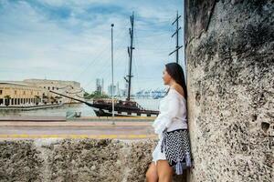 Beautiful woman standing at the walls of Cartagena de Indias looking to the bay photo