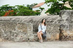 Beautiful woman on white dress sitting alone at the walls surrounding the colonial city of Cartagena de Indias photo