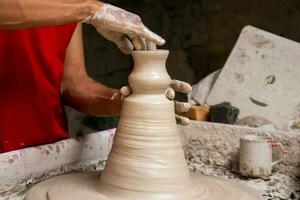 hombre haciendo cerámico artículos en el alfareros rueda en un tradicional fábrica en el ciudad de ráquira situado en el Departamento de cundinamarca en Colombia foto