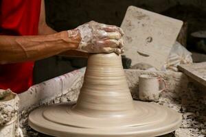 Man making ceramic articles on the potters wheel in a traditional factory in the city of Raquira located in the department of Cundinamarca in Colombia photo