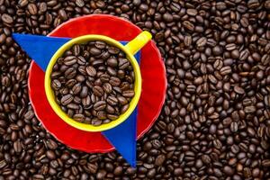 Cup filled with Colombian coffee beans and the colors of the Colombian flag over a background of roasted coffee beans photo